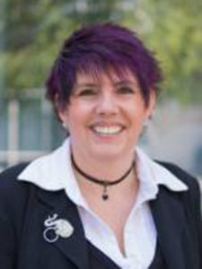 Woman with purple hair wearing black suit jacket and white shirt